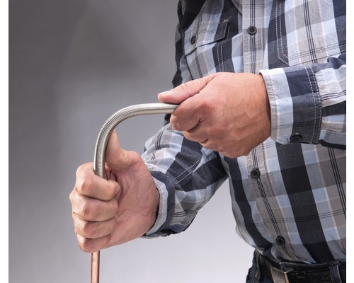 Een persoon buigt een flexibele metalen buis.