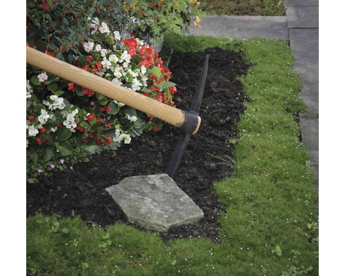 Tuinscene met een houweel, bloemen en gras