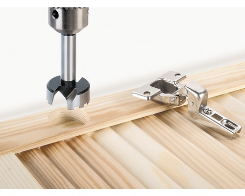 Forstnerboor boort gat naast meubelscharnier in een houten plank