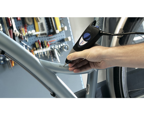 Een man gebruikt een graveermachine om een nummer in een fietsframe te graveren.