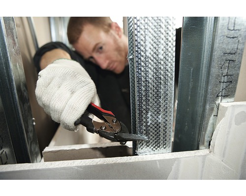 Man knipt metalen profiel met blikschaar