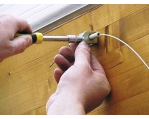 Een persoon monteert een jaloezie met een schroevendraaier.