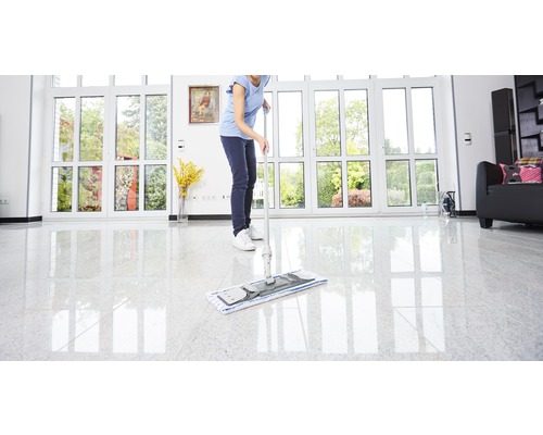 Vrouw dweilt vloer met een mop in een heldere kamer.