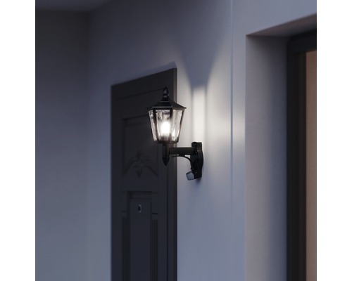 Brandende buitenwandlamp met bewegingsmelder naast een deur