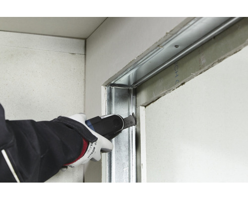 Een vakman snijdt met een multifunctioneel gereedschap een metalen structuur op een gipsplaat