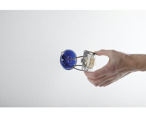 Hand monteert een lichtschakelaar in een wandcontactdoos.