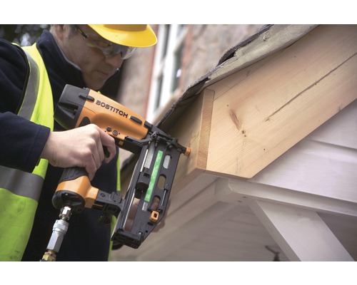 Ambachtsman bevestigt hout met een Bostitch pneumatische tacker aan een dakrand.