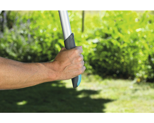 Hand houdt tuingereedschap met handvat in de tuin vast