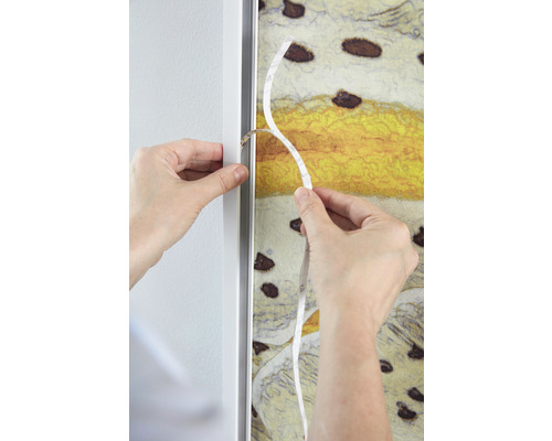 Persoon bevestigt een canvas met tape in een fotolijst.