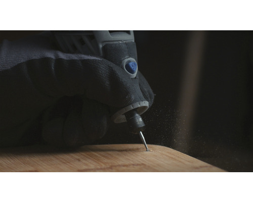 Hand met beschermende handschoen gebruikt een multifunctionele schuurmachine op een houten plank.