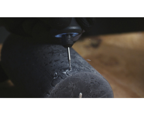 Close-up van een graveermachine die een patroon in een donkere kaars snijdt