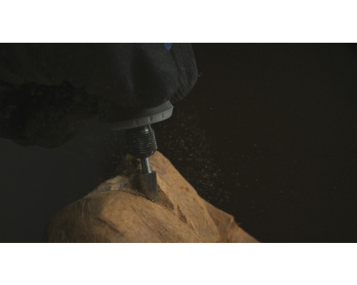 Een hand met een werkhandschoen bewerkt hout met een multifunctioneel gereedschap.