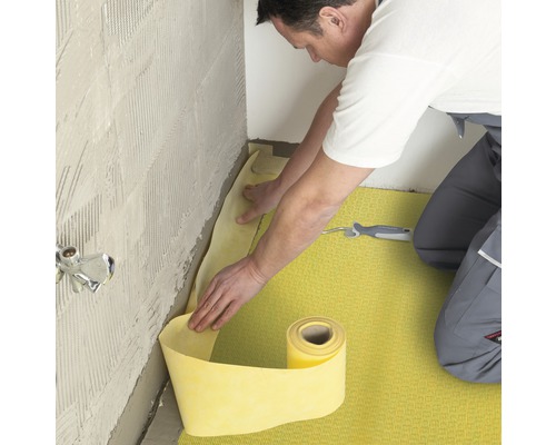 Een man legt een afdichtingsbaan in de badkamer.