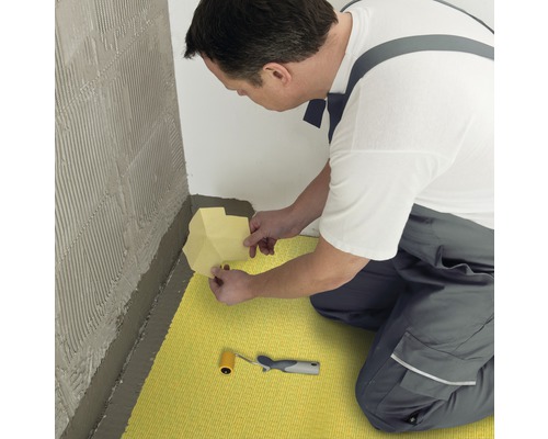 Ambachtsman installeert ontkoppelingsmat op de vloer en muur met gereedschap voor tegelwerk