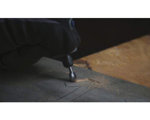 Een persoon gebruikt een multifunctioneel gereedschap om in een stuk hout te snijden.