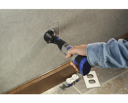 Een persoon gebruikt een multifunctioneel gereedschap om een opening in een muur te snijden voor een stopcontact.