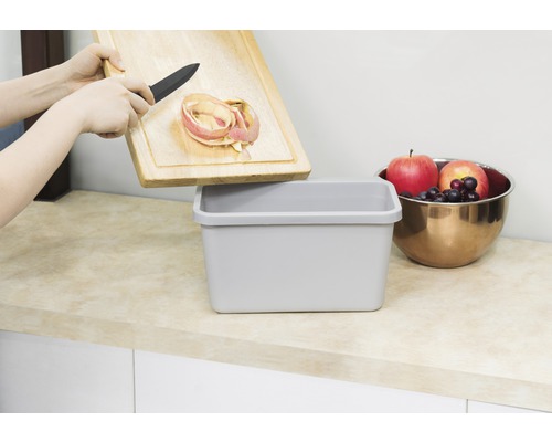 "Iemand gooit appelschil van een houten plank in een afvalbak