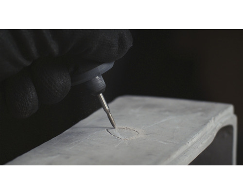 Een persoon graveert een object met een graveermachine.