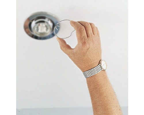 Hand houdt een borgveer vast voor een inbouwspot.