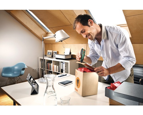 Man sluit een doos met een accutacker in een kantoor.