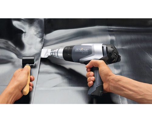 Iemand gebruikt een Steinel heteluchtpistool HG 2320 E en een aandrukrol voor de verwerking van dakbedekking.