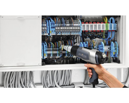 Elektricien werkt met heteluchtpistool aan verdeelkast