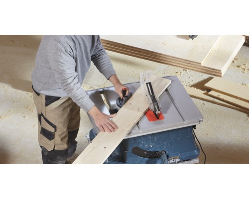 Een persoon zaagt een houten plank met een tafelzaag.