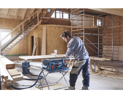 Een man werkt met een tafelzaag in een casco gebouw.