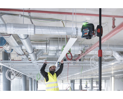 Een arbeider met veiligheidshelm en veiligheidsvest installeert een plafond met een laserwaterpas van Bosch.