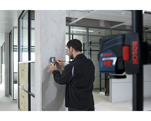 "Een man gebruikt een digitale meter op een betonnen muur