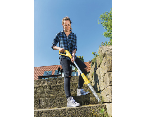 Een vrouw verwijdert onkruid met een elektrische onkruidverwijderaar op een stenen trap.