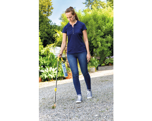 Een vrouw verwijdert onkruid met een gasbrander in de tuin.