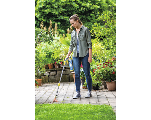 Vrouw gebruikt een gasbrander voor onkruidbestrijding op een terras.