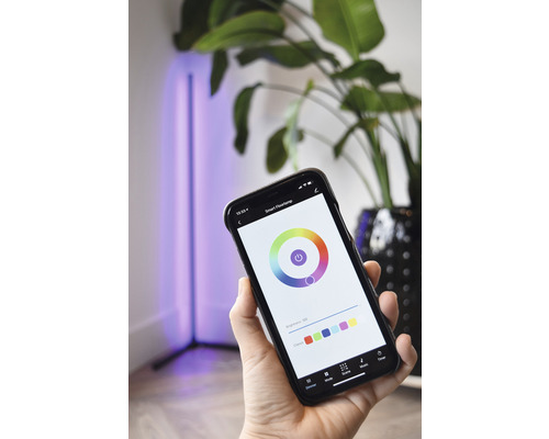 Persoon bedient een staande slimme lamp met een app op een smartphone.