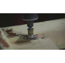 Een multifunctioneel gereedschap met borstelopzetstuk schuurt hout.