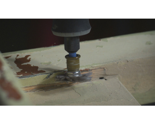 Een multifunctioneel gereedschap met borstelopzetstuk schuurt hout.