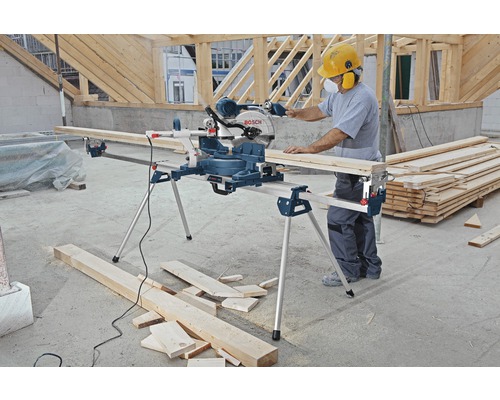 Man werkt met een Bosch verstekzaag met werkbank op een bouwplaats