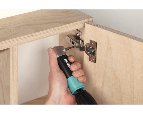 Iemand bevestigt een meubelscharnier met een haakse schroevendraaier aan een houten kast.
