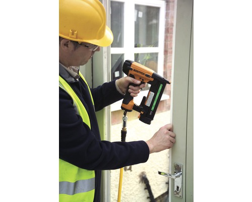 Man bevestigt een raamkozijn met een pneumatische tacker.