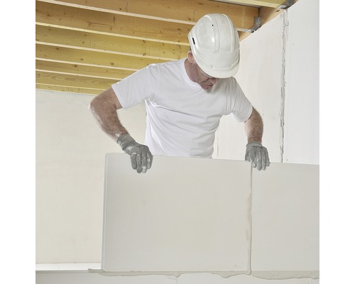 Een man met een veiligheidshelm en handschoenen plaatst cellenbetonblokken