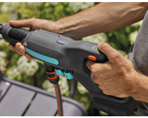 Een persoon bedient een Gardena tuindouche met accu