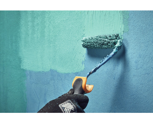 Een persoon schildert een muur met een verfroller.