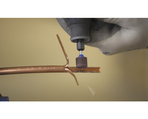 Een persoon gebruikt een multifunctioneel gereedschap om een buis te snijden.