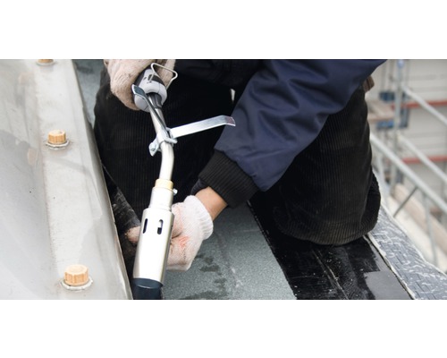 Een dakdekker last een dakbedekking met een brander.