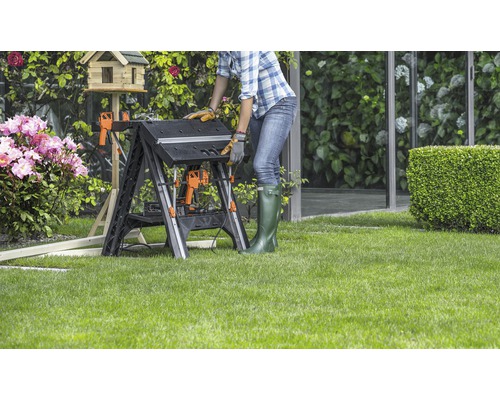 Vrouw werkt aan een opklapbare werkbank in de tuin.
