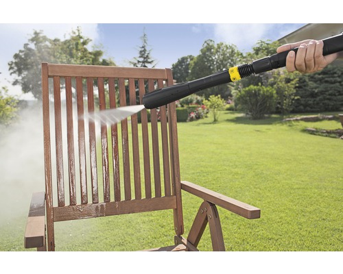 Hogedrukreiniger in gebruik voor het reinigen van een houten stoel in de tuin.