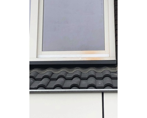 Detailaanzicht van een dak met dakpannen en een raam.