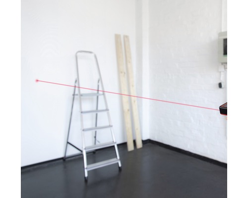 Kamer met ladder, houten planken en laser afstandsmeter met rode laserstraal