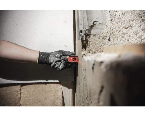 Iemand gebruikt een lasernivelleerapparaat op een muur om een project uit te lijnen.