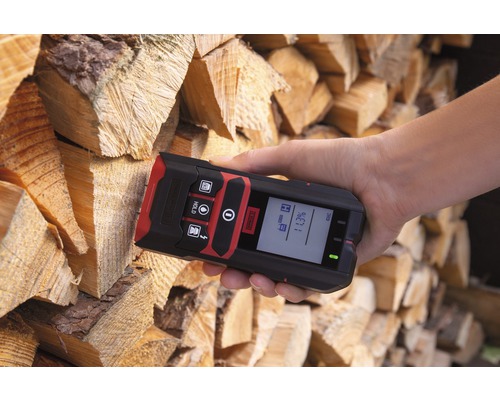 Hand met een houtvochtmeter voor een stapel hout